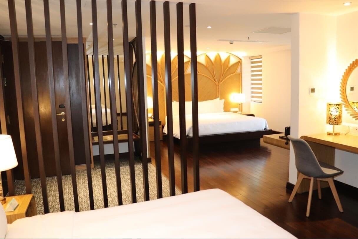 A hotel room with a bed, a desk, a chair, and a decorative wall panel.