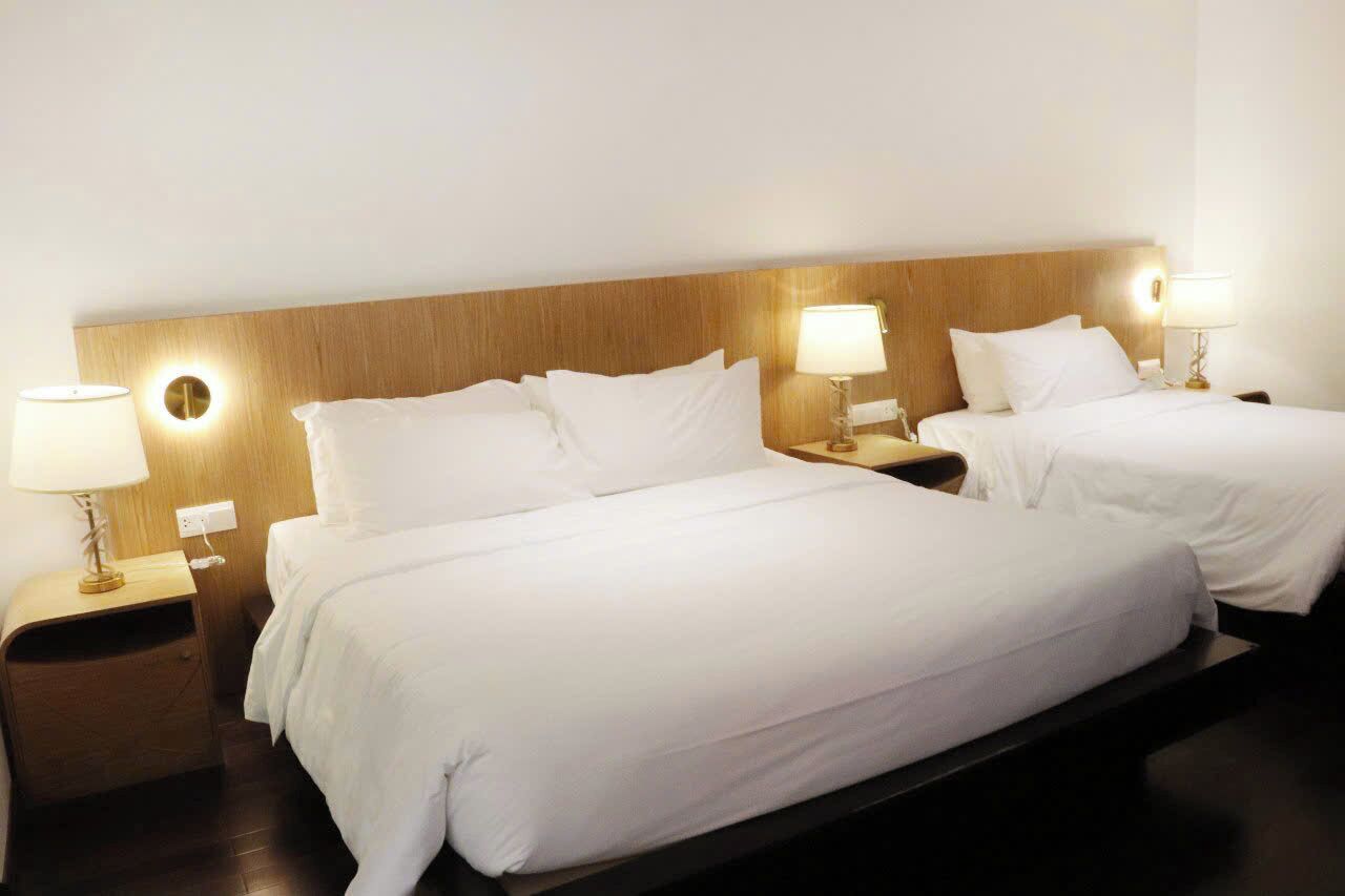 Une chambre d’hôtel avec deux lits simples, chacun étant équipé d’une table de chevet et d’une lampe.