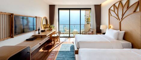 Habitación de hotel con dos camas, un escritorio con computadora, una silla, un ventanal con vista y un espejo decorativo.