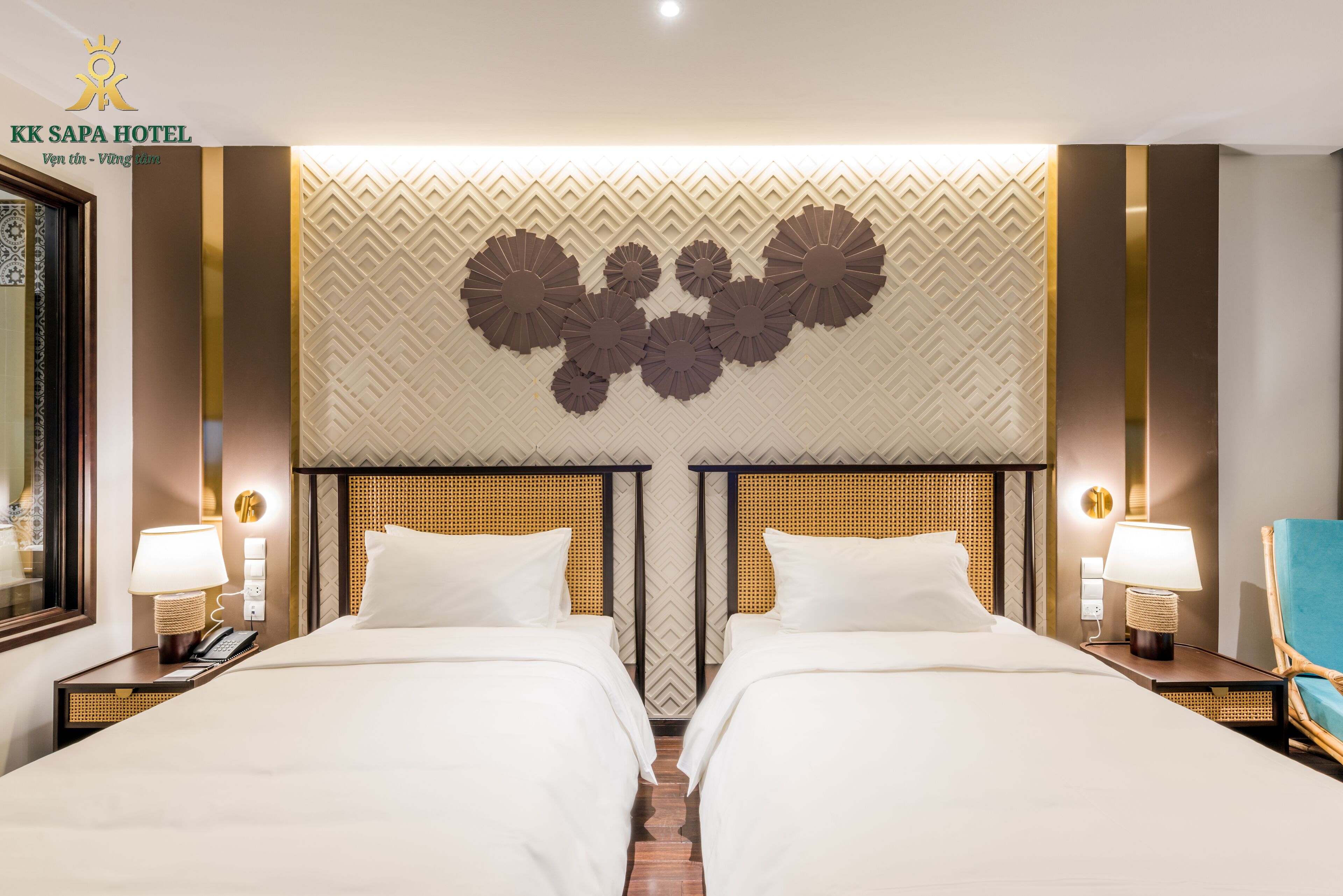 Una habitación de hotel con dos camas, un adorno en la pared y una mesita de noche con lámpara.