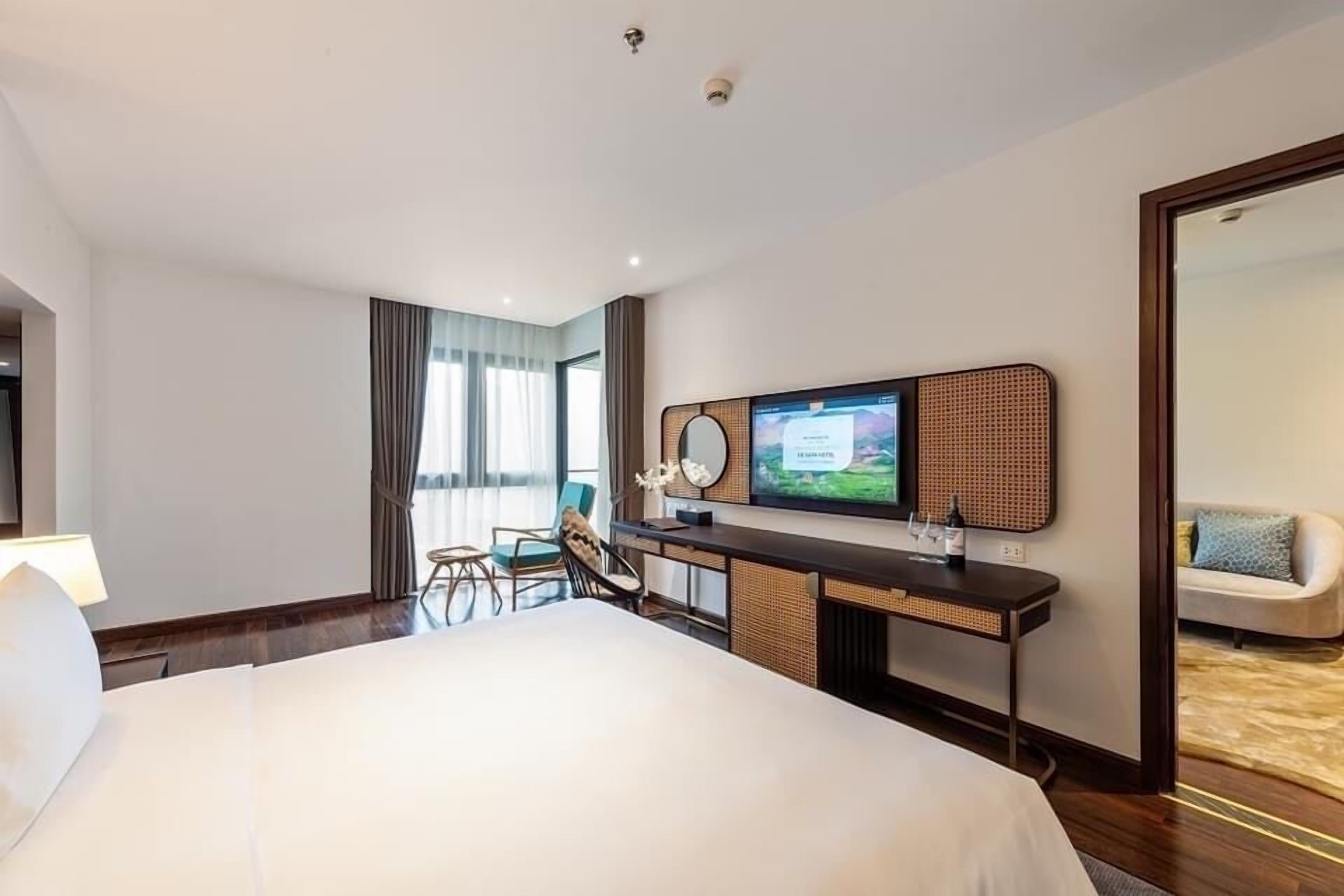 Habitación de hotel con una cama grande, un escritorio con televisor de pantalla plana, una silla y un sofá.