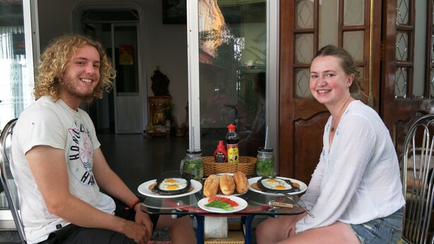 Dos personas sentadas en una mesa con platos de comida, una cesta y salsas.