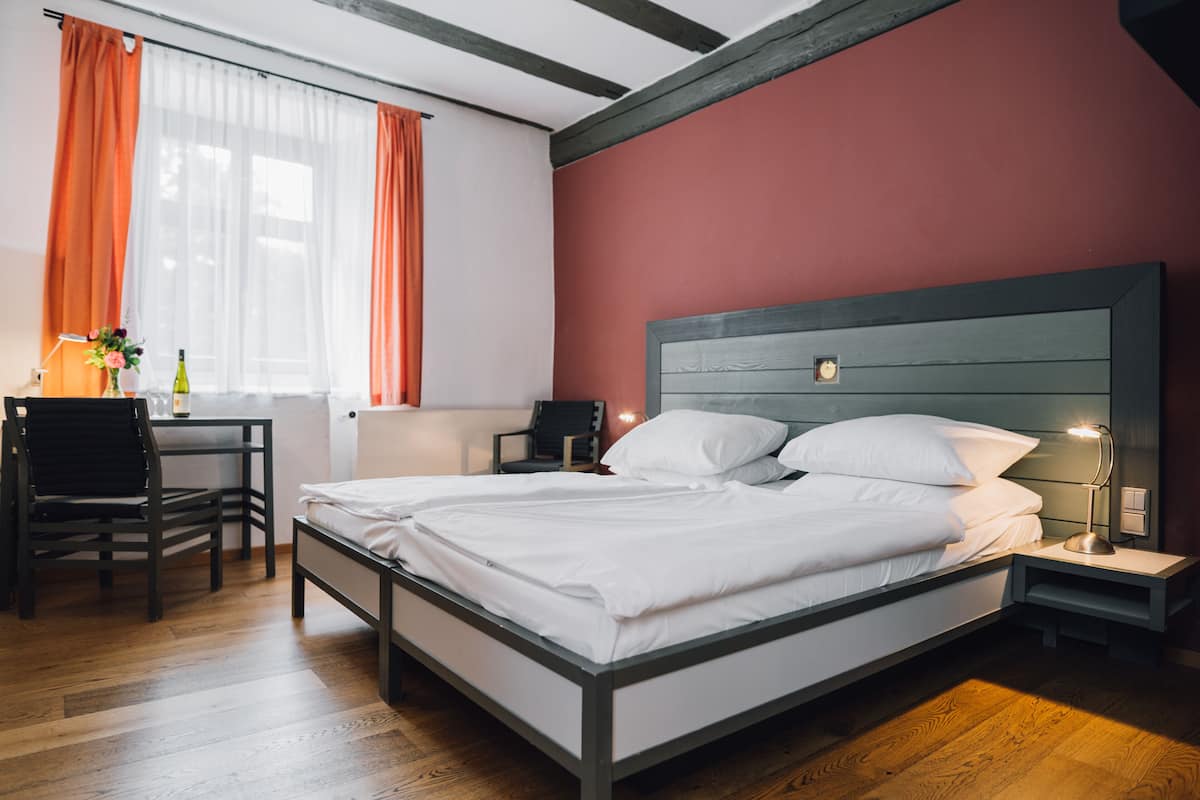 Une chambre à coucher comprenant un lit, une table de chevet, une chaise et un bureau avec une lampe.