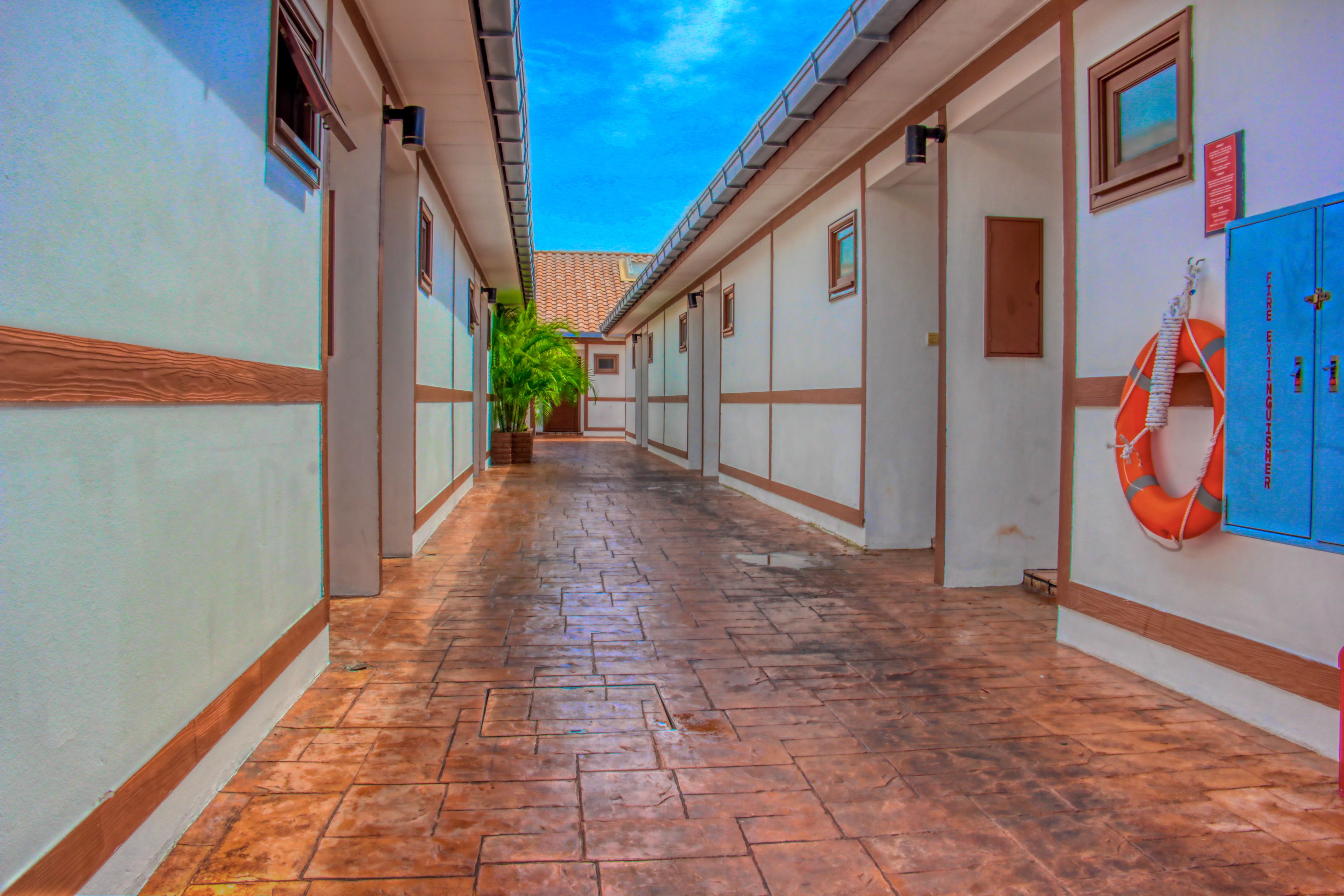 A corridor with tiled flooring, wooden trim, and a blue locker on the right.