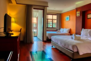 A hotel room with two beds, a television, a desk, and a window with curtains.
