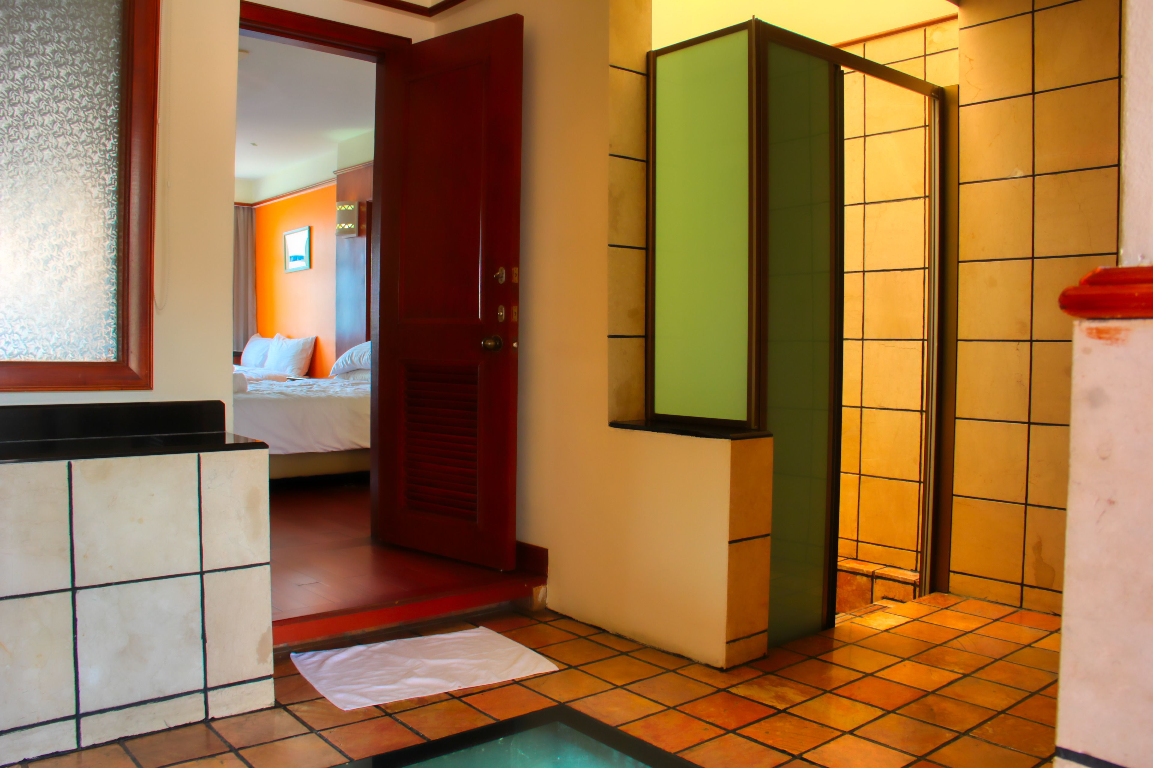 Habitación de hotel con cama, baño con ducha y una pequeña zona de piscina.