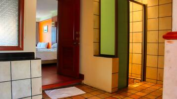 Habitación de hotel con cama, baño con ducha y una pequeña zona de piscina.