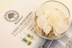 A glass bowl with white flowers and a brochure with text and images of products. - White House (Taitung)