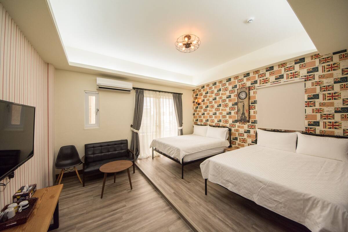 A hotel room with a skylight, a bed, a desk, a TV, and a wall with a flag pattern.