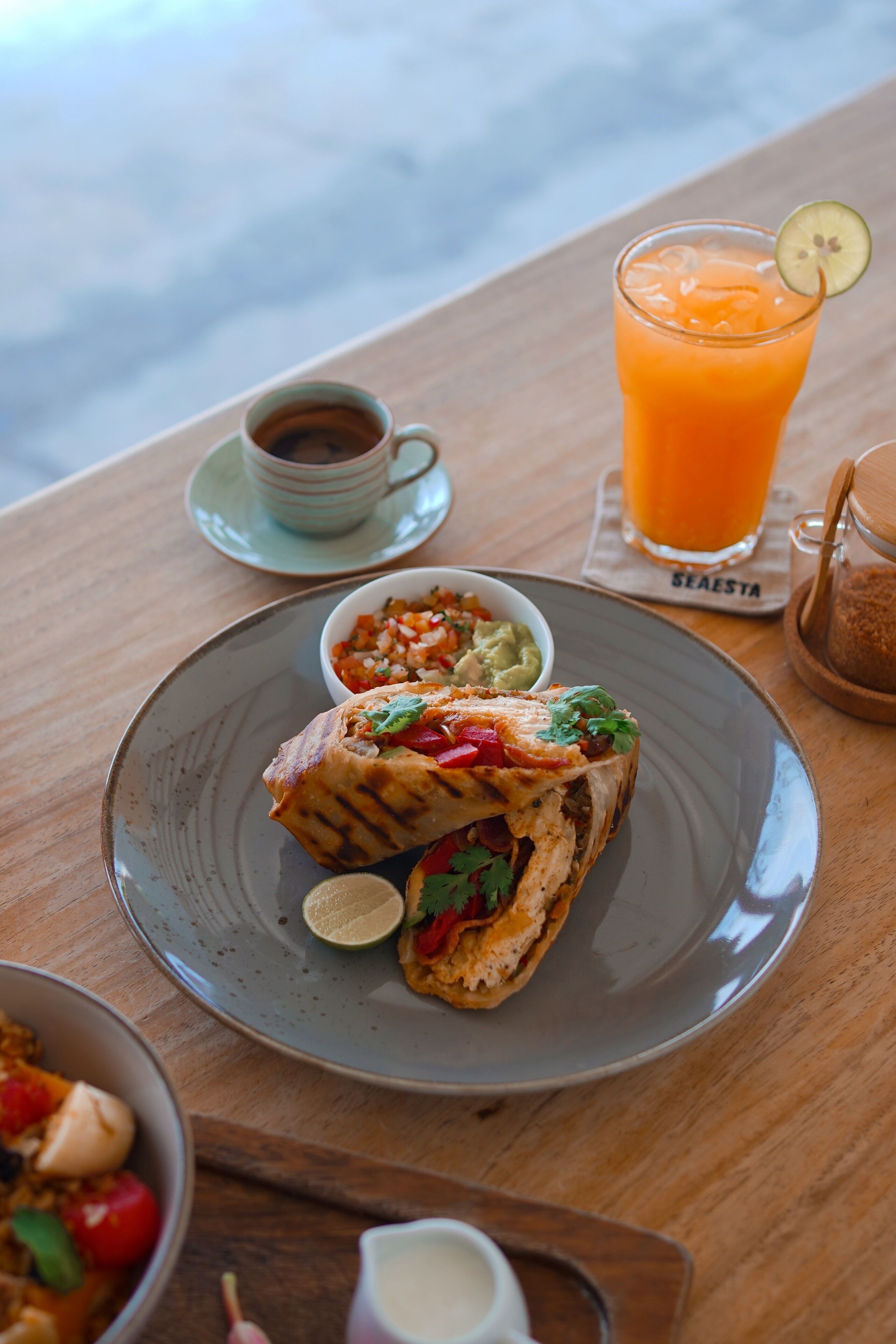 A meal with a sandwich, a glass of orange juice, and a cup of coffee on a wooden table.