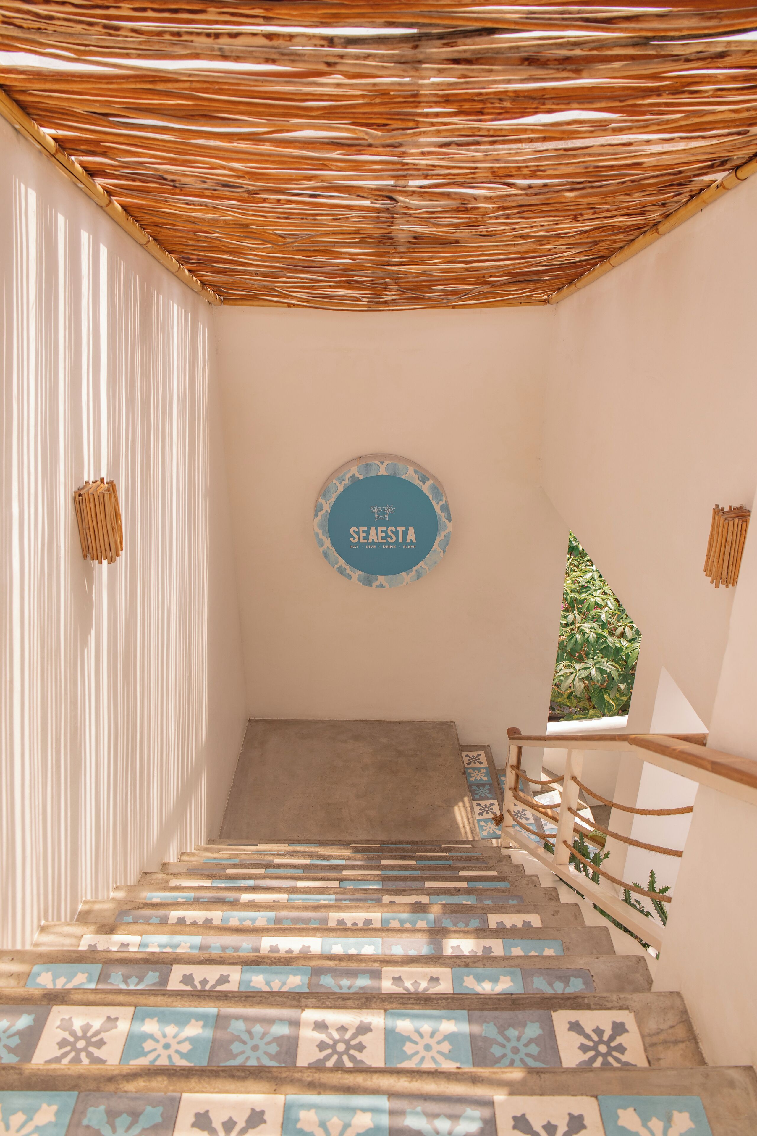 A staircase with patterned tiles leading to a room with a 'SEASTA' sign.