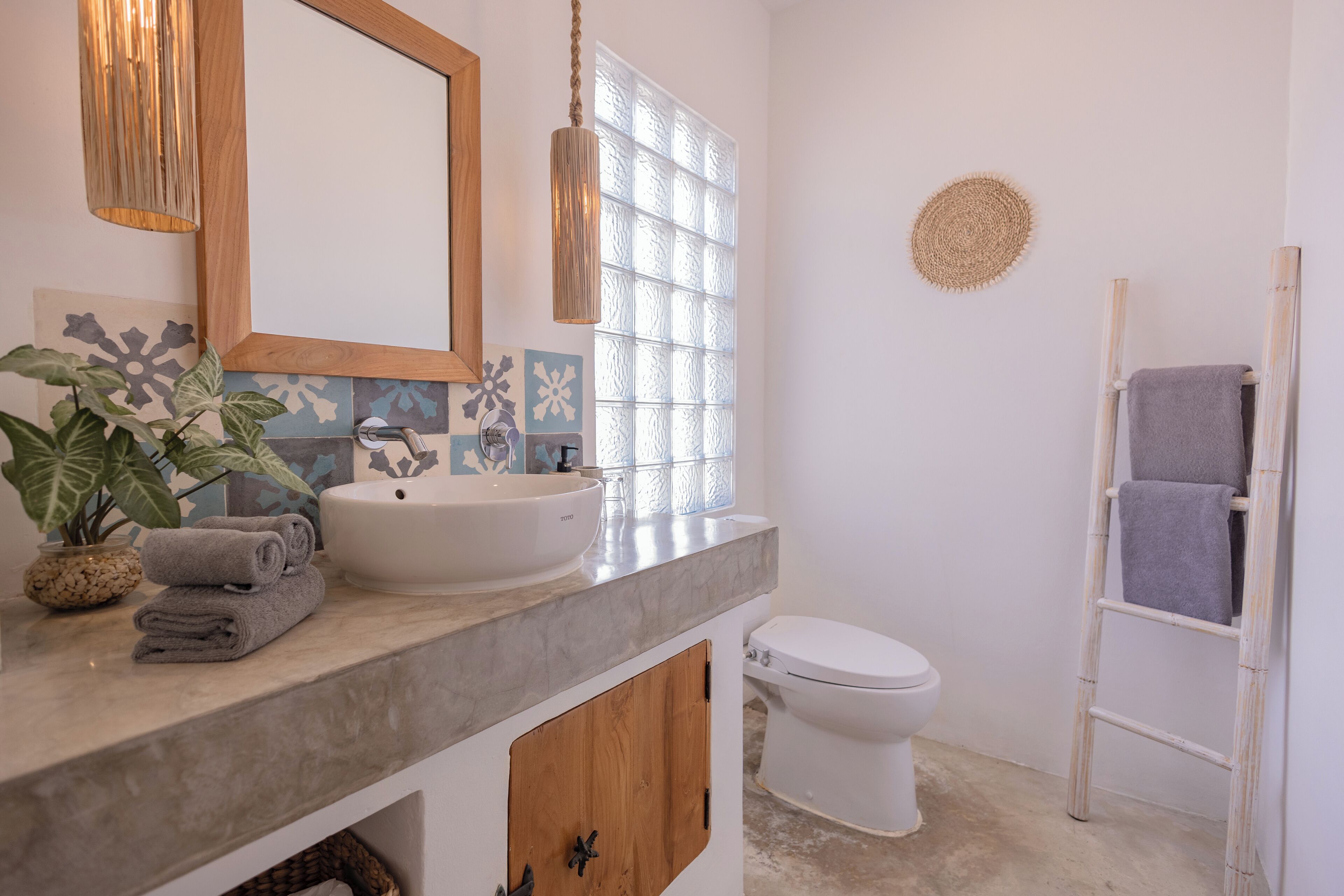A bathroom with a white sink, a mirror, a toilet, and a towel rack.