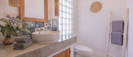 A bathroom with a white sink, a mirror, a toilet, and a towel rack.