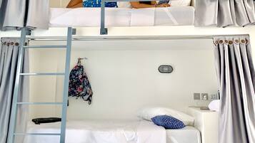 A bunk bed room with a ladder, a small table, and a wall-mounted light.