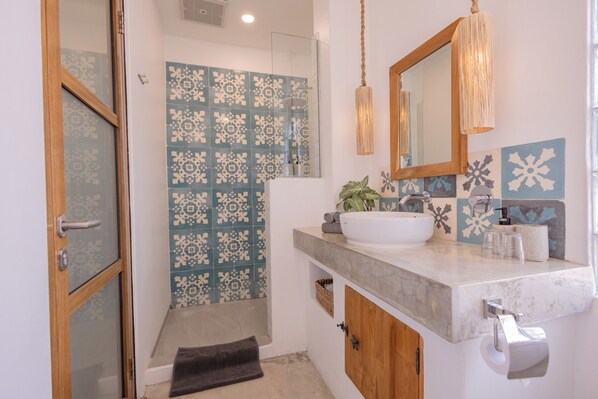 A bathroom with a shower, a sink, and a mirror.