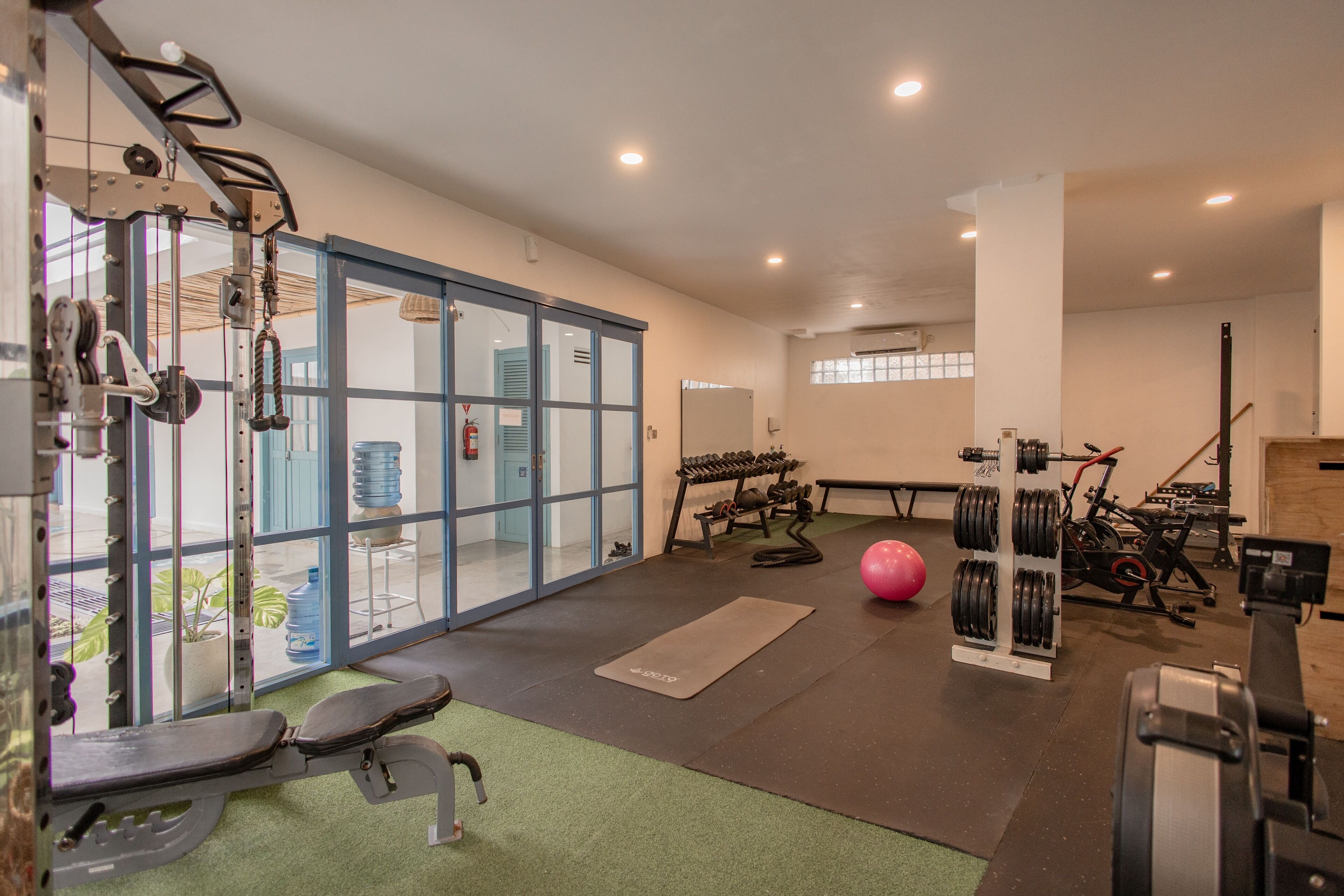 A gym with exercise equipment, a bench, a yoga mat, and a large water dispenser.
