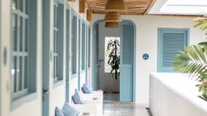 A corridor with white walls, blue shutters, and a wooden ceiling.