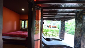 Un dormitorio con cama, ventana con cortinas y vista a zonas verdes.