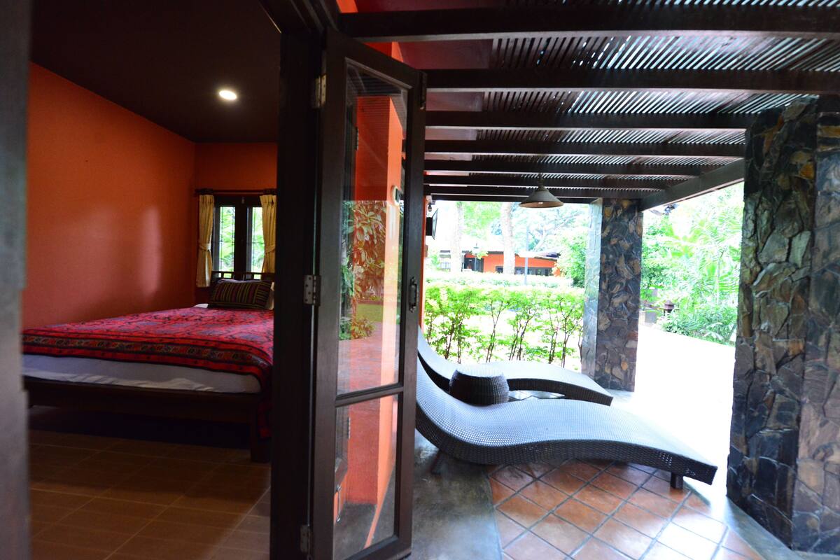 Un dormitorio con cama, ventana con cortinas y vista a zonas verdes.