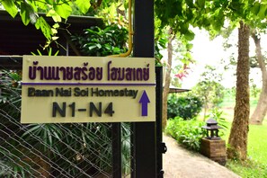 A sign for a homestay named "Baan Nai Soi Homestay" with directional arrows pointing to the north. - Baan Nai Soi Homestay (Saraphi)