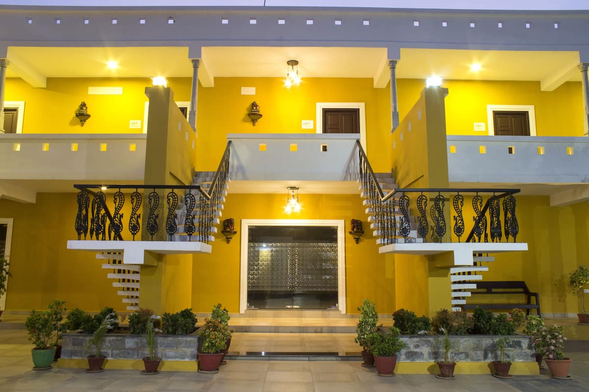 A two-story building with a central entrance, a staircase on each side, and potted plants in front.
