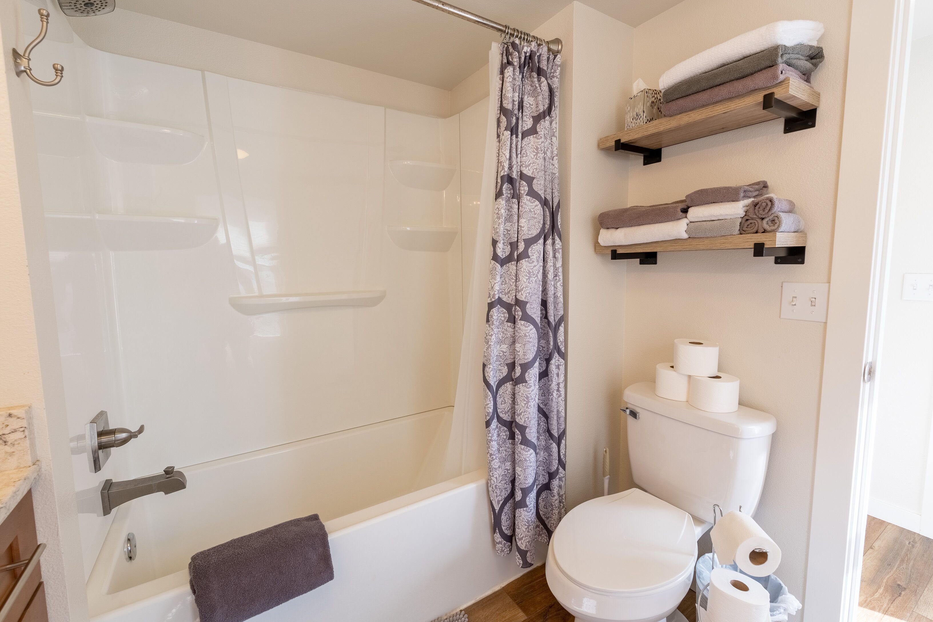 Et badeværelse med brusebad, toilet og håndklædeholdere.