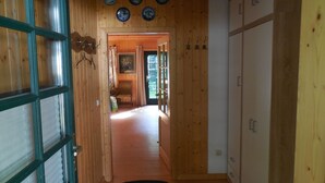 A wooden hallway with a door leading to a room, a black mat at the entrance, and a wall with circular decorations. - Cozy wooden cottage with Wi-Fi and feel-good atmosphere (Bohmte)