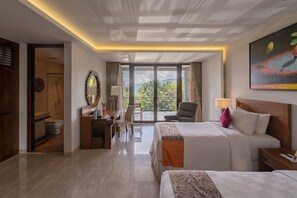 Habitación de hotel con una cama grande, un escritorio con una silla, una mesita y vistas al exterior a través de una puerta corrediza.