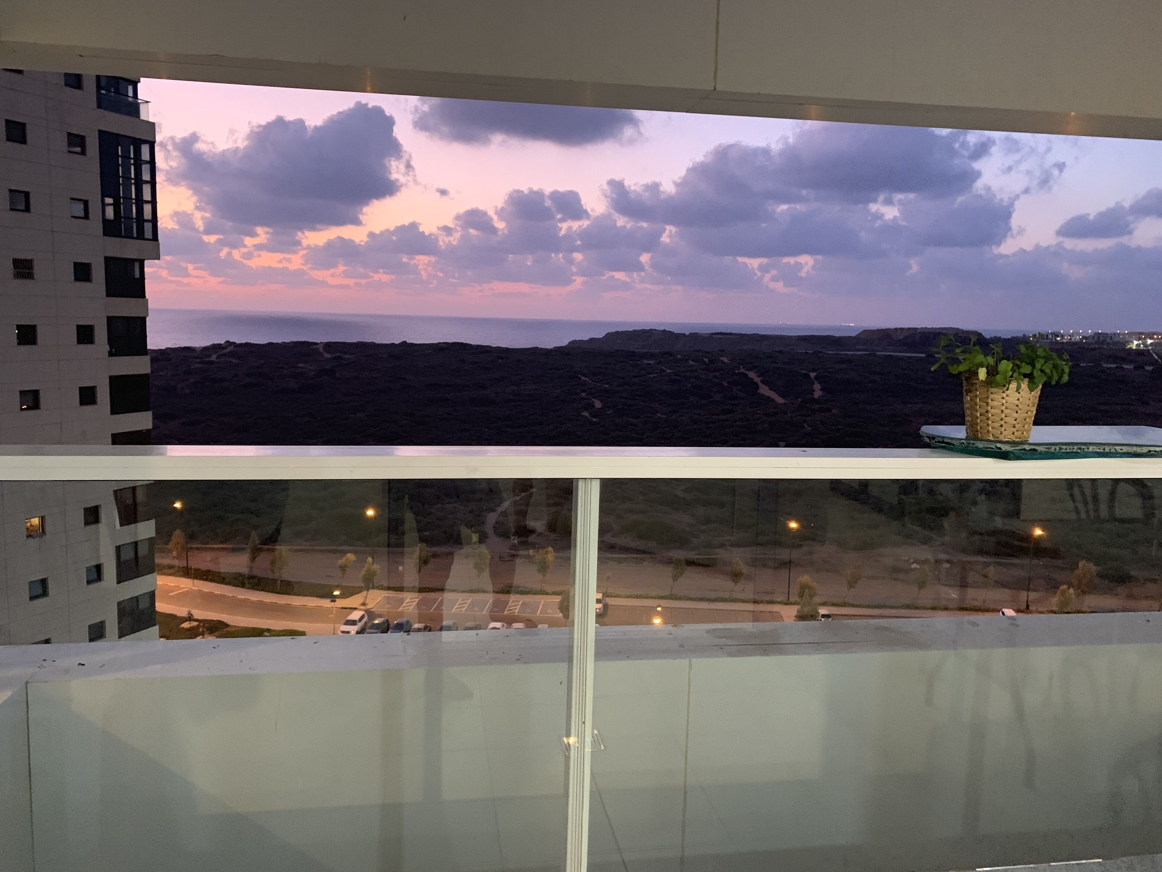 A balcony with a view of a mountainous landscape and a sunset.