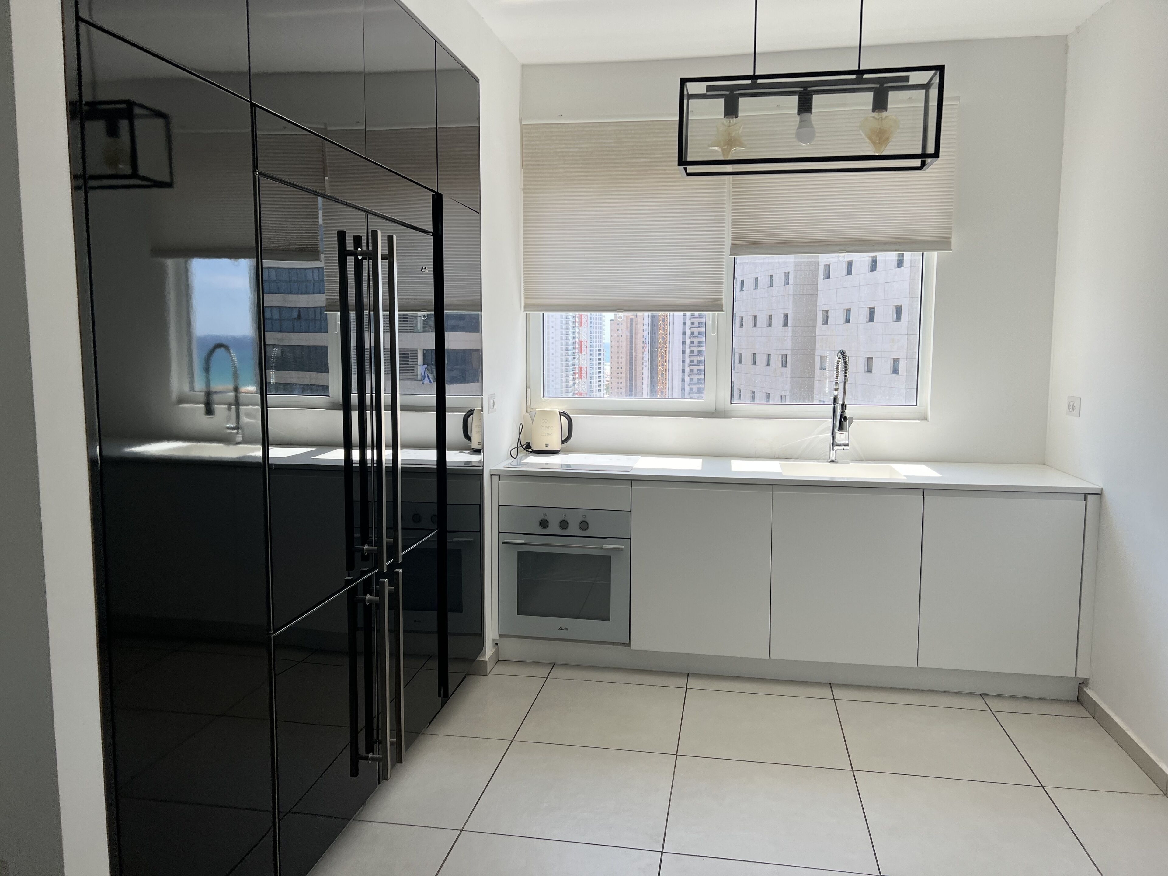 A modern kitchen with a large window, a built-in oven, and a coffee maker.
