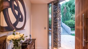 Een modern interieur met een houten bank, een vaas witte bloemen en een stenen pilaar buiten.