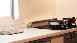 A kitchen with a sink, a dish rack, a stove, and a pot. - Aguri Home (Osaka)