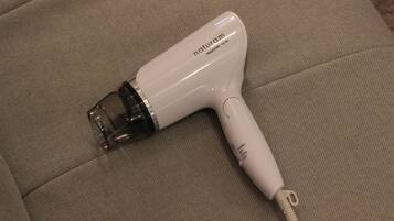 A white hair dryer with the brand name 'naturam' and model 'TESCOM 1100' on a beige couch.
