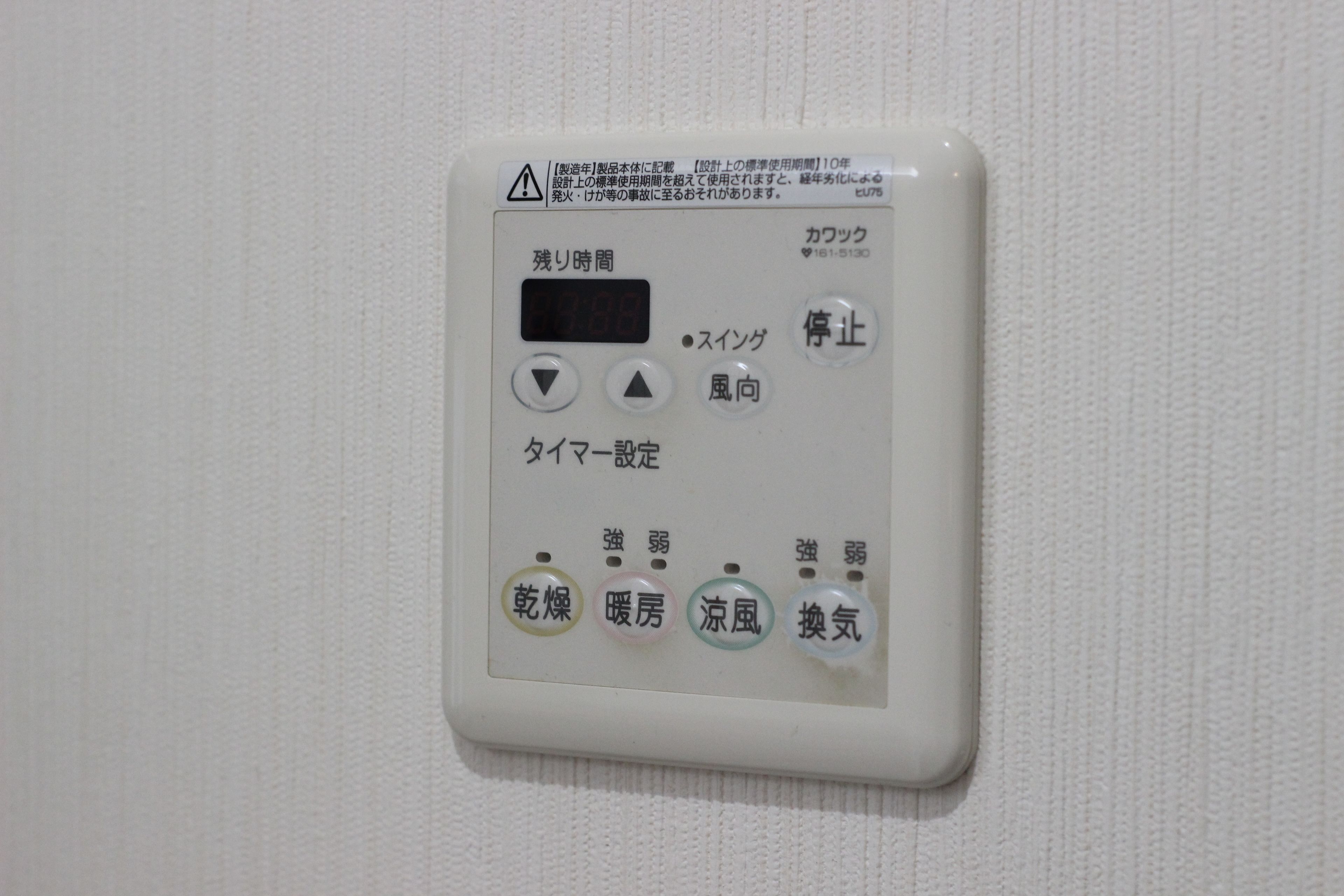 A control panel with a digital display, buttons, and labels in Japanese.