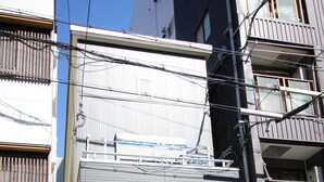 A modern building with a flat roof, a visible entrance, and a bicycle parked outside. - Aguri Home (Osaka)