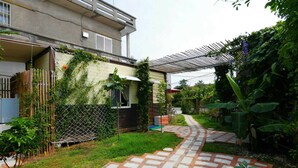 A residential garden with a paved pathway, a wooden fence, and a variety of plants. - Fan Zai Cuo (Liuqiu)