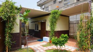 A residential building with a covered patio area, a small garden, and a bamboo fence. - Fan Zai Cuo (Liuqiu)