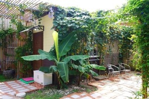 Uma área de pátio com piso de azulejos, um armário branco e uma cadeira de metal.