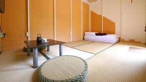 A tatami mat room with a low table, a pillow stack, and a hanging decorative item. - Fan Zai Cuo (Liuqiu)