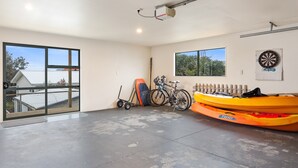 Un garage spacieux doté d’une grande porte coulissante, d’un projecteur fixé au plafond, d’un jeu de fléchettes et d’un kayak.