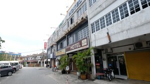 Ein Hotel mit einem Schild, auf dem 'Nice Stay' und 'Hotel' steht. Vor der Fassade befinden sich Blumentöpfe und ein geparktes Motorrad.