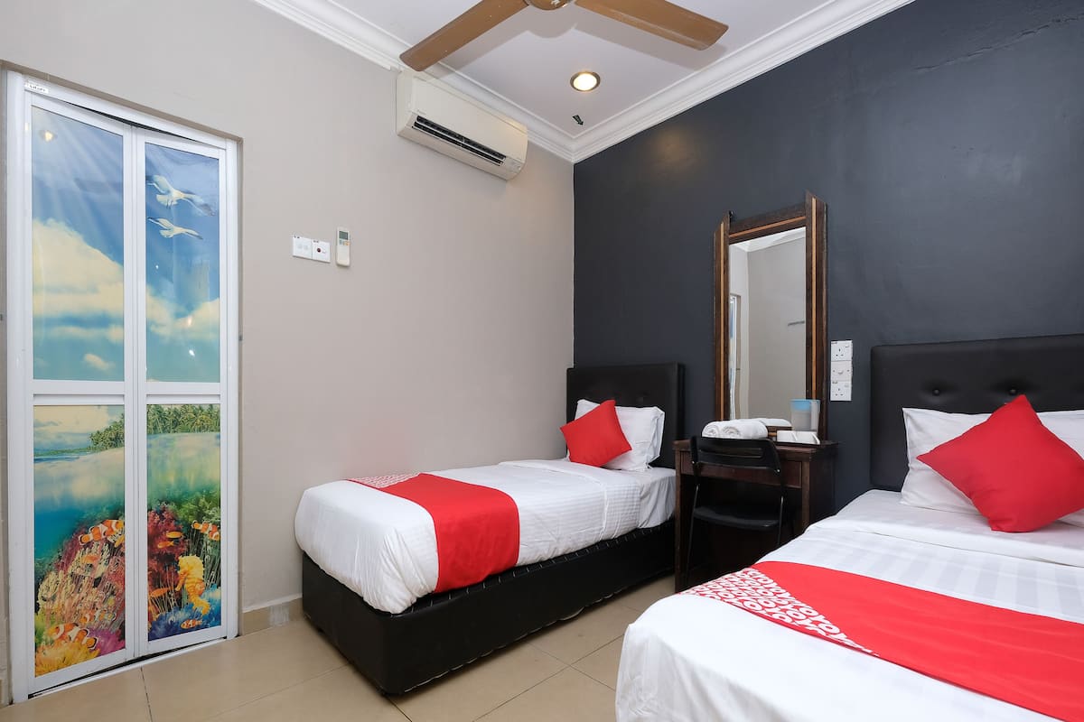 Ein Hotelzimmer mit zwei Betten, einem Deckenventilator, einer Klimaanlage, einem Badezimmerspiegel und einer Tür mit einem tropischen Wandbild.