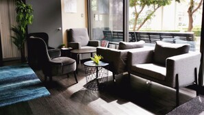 Un espace de détente moderne comprenant un canapé, des fauteuils, une petite table et une plante en pot.