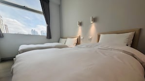 Une chambre d’hôtel avec un grand lit, une fenêtre avec des rideaux et deux lampes fixées au mur.