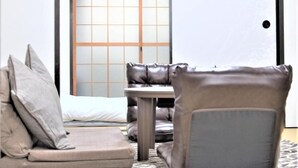 A traditional Japanese-style room with tatami flooring, a low table, and cushions. - U-SHUKU Osaka (Osaka)