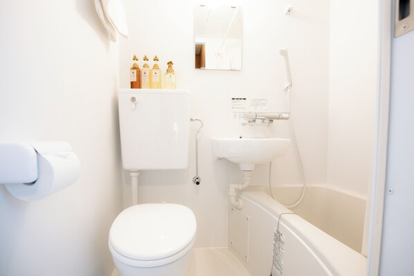 A white bathroom with a toilet, sink, and bathtub. There are toiletries on the wall and a mirror above the sink. - U-SHUKU Osaka (Osaka)