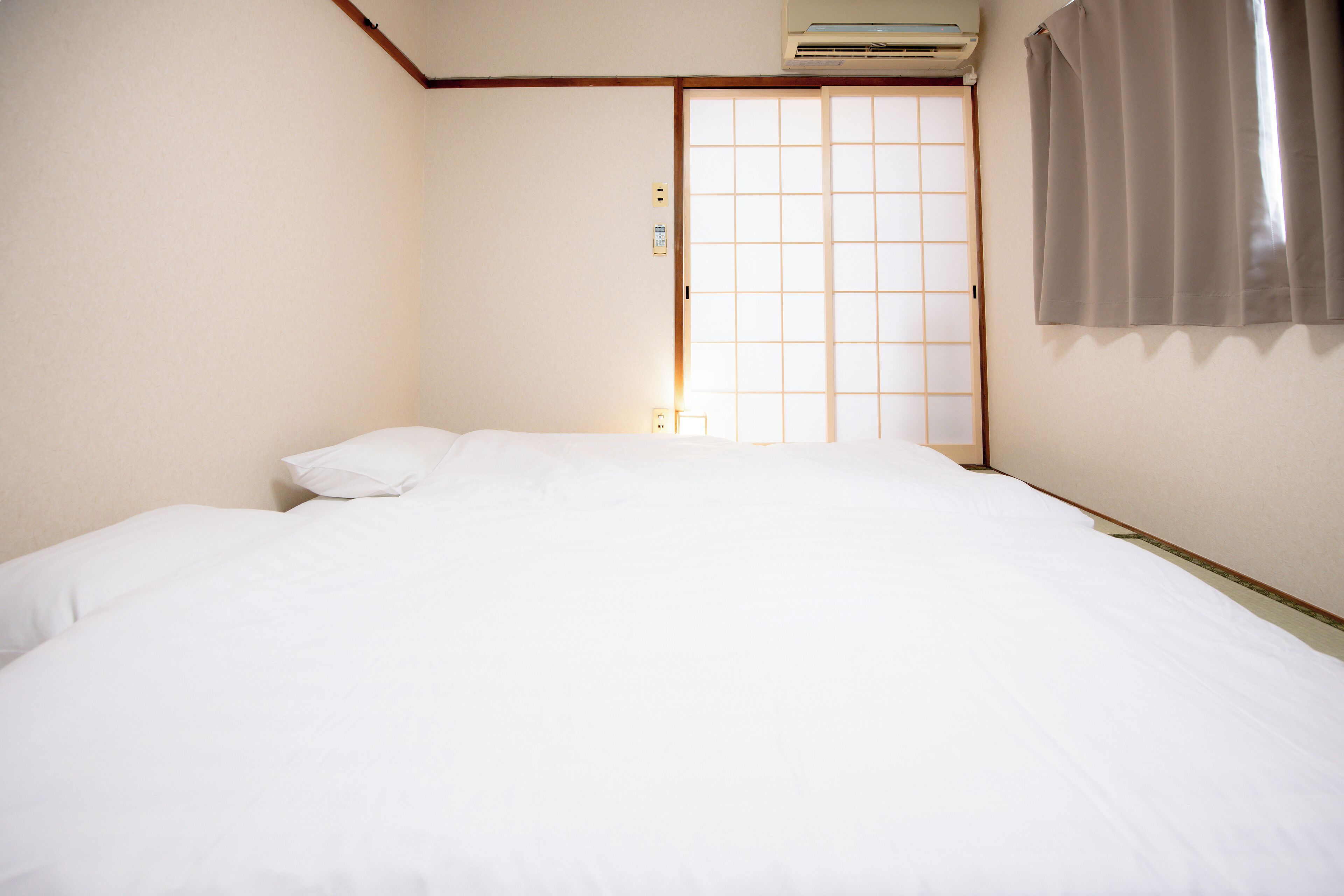 A hotel room with a bed, a sliding door, and an air conditioning unit.