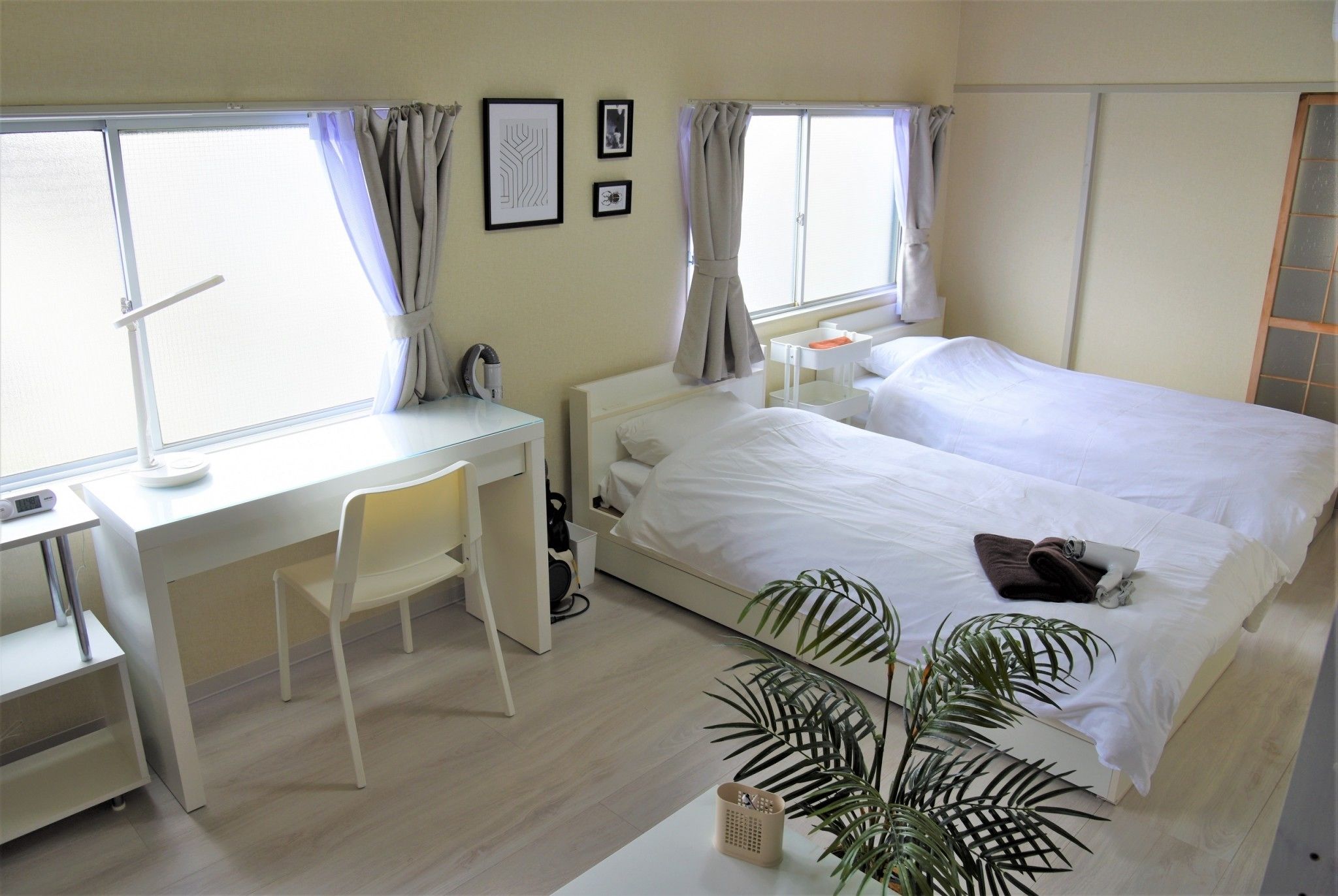 A hotel room with a bed, desk, chair, and a potted plant.