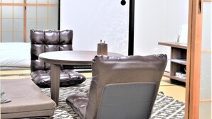 A room with a round table, two leather chairs, a sofa, and a patterned rug. - U-SHUKU Osaka (Osaka)