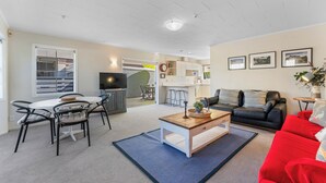 Een moderne woonkamer met een eethoek, een keuken op de achtergrond en een rode bank.